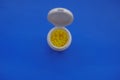 Yellow pills in white plastic container close-up on blue background. Copy space. Top view. Medicine, healthcare, prevention