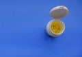 Yellow pills in white plastic container close-up on blue background. Copy space. Top view. Medicine, healthcare, prevention