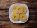Yellow pineapple rings on a white plate on a wooden table top view. Royalty Free Stock Photo