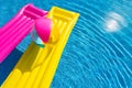 Yellow and pink air beds with beachball on swimming pool water Royalty Free Stock Photo