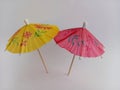 Yellow and pink miniature drink umbrellas open on a white background Royalty Free Stock Photo