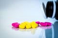 Yellow and pink oval tablet pills with shadows on white background with blurred pills bottle. Mild to moderate pain management.