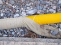 Yellow pipe on stone pebbles. Technical communications on the beach. Cable Royalty Free Stock Photo