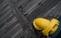 A yellow pipe on the wooden deck of a ship.