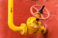 Yellow pipeline with valve against the red wall Royalty Free Stock Photo