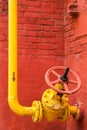 Yellow pipeline with valve against the red wall Royalty Free Stock Photo