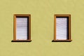 yellow plaster wall of an old house with window and closed shutter blinds Royalty Free Stock Photo