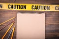 Yellow plastic caution tape and a notepad on a wooden table