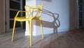 Yellow plastic chair near the wall with a shadow in the interior of the house Royalty Free Stock Photo