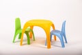 Yellow plastic childrens table and two chairs on white background