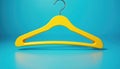 Yellow plastic clothes hanger isolated on bright blue backdrop. Simple object for garment or apparel display. Clean minimal Royalty Free Stock Photo