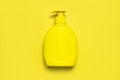 Yellow plastic cosmetic bottle container with dispenser on yellow background flat lay top view Clean container without label for Royalty Free Stock Photo