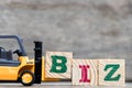 Yellow plastic forklift hold letter B to complete word biz & x28;Abbreviation of business& x29; Royalty Free Stock Photo