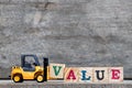 Yellow plastic forklift hold letter V to word value Royalty Free Stock Photo