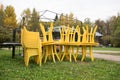 Yellow plastic furniture in an open-air clearing. The furniture is stacked on top of each other. End of the holiday