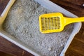 Yellow plastic scoop on the gray litter box, filled by blue litter sand