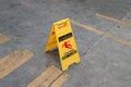 Yellow plastic sign with red symbol of slip and black text of caution wet floor on the floor. Royalty Free Stock Photo