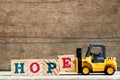 Yellow plastic toy forklift hold letter block E to word hope Royalty Free Stock Photo