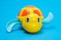 Yellow plastic turtle for playing in the water on a blue background. Toys for babies for bathing.