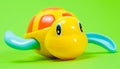 Yellow plastic turtle for playing in the water on a green background. Toys for babies for bathing