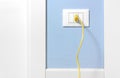 Yellow Plug in a Wall Socket on a Blue Wall Royalty Free Stock Photo