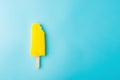 Yellow popsicle with a bite on blue