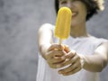 Yellow popsicle in happy smiling beautiful Asian woman`s hand. Royalty Free Stock Photo