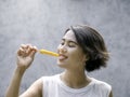 Yellow popsicle in happy smiling beautiful Asian woman`s hand. Royalty Free Stock Photo