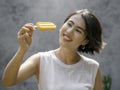 Yellow popsicle in happy smiling beautiful Asian woman`s hand. Royalty Free Stock Photo