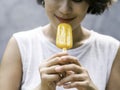 Yellow popsicle in happy smiling beautiful Asian woman`s hand. Royalty Free Stock Photo