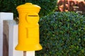 Yellow post box in green garden. Decorative postbox closeup photo. Vintage mail box and green hedge