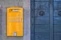 Yellow post box on the wall next to a blue metal door Royalty Free Stock Photo