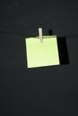 Yellow post it note with wooden clothespin hanging on rope thread with dark background copy space vertical annotation Royalty Free Stock Photo