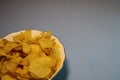 Potato chips in a plate on a gray background.