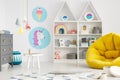 Yellow pouf in colorful child`s room interior with lamps and pos