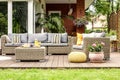 Yellow pouf and flowers next to rattan garden furniture on wooden terrace of house. Real photo Royalty Free Stock Photo