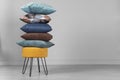 Yellow pouf on steel legs with pillows in a stack, on a gray background. Space for text