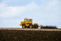 Yellow powerful wheeled tractor pulls the disc harrow