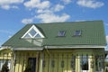 A yellow private house under a green tiled roof with windows Royalty Free Stock Photo