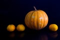 Yellow pumpkin and oranges photo on black background. Royalty Free Stock Photo