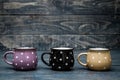 Yellow, Purple and Black Ceramic Mugs with White Dots on Blue Wooden Background Royalty Free Stock Photo