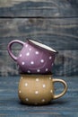 Yellow and Purple Ceramic Mug with White Dots on Blue Wooden Background Royalty Free Stock Photo