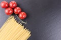 Yellow raw spaghetti and cherry tomatoes on black slate plate Royalty Free Stock Photo