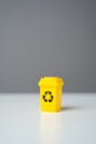 Yellow recycling bin on gray background.