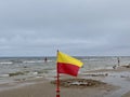 A Yellow and red beach flag, warning flag, lifesaving surf flag, rainy day in the beach, beach storm attention