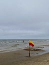 A Yellow and red beach flag, warning flag, lifesaving surf flag, rainy day in the beach, beach storm attention