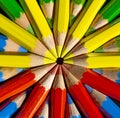 Yellow,red,blue and green colored pencils in the round formation on the black background close up .