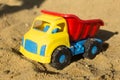 Yellow red and blue truck toy in sand, on the beach. Royalty Free Stock Photo