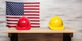 yellow and red builders helmets on a wooden table against the background of the flag.