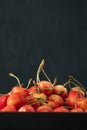 Yellow-red cherries on platter on black background. Ripe juicy cherries. Seasonal berries. Vertical frame